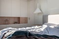 Sunny modern bedroom with white walls and hanging lamp