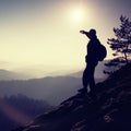 Sunny morning. Hiker is standing on the peak of rock in rock empires park and watch over misty and foggy morning valley