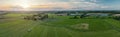 Sunny panorama of rural idyll with agricultural factory, fields, and tractor with slurry tanker by the work in the countryside. M