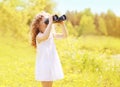 Sunny photo child looks in binoculars outdoors in warm summer