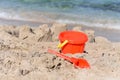 A sunny photo with a children`s beach pail and a spatula against a background of a sea