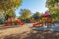 Sunny playground with slides and climbing frames surrounded by trees Royalty Free Stock Photo