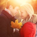 Sunny portrait happy young smiling couple in love with autumn maple leaf outdoors on warm sunset Royalty Free Stock Photo