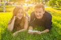 Sunny portrait of sweet young couple lying relaxing on the grass together listens to music in earphones on smartphone Royalty Free Stock Photo