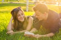 Sunny portrait of sweet young couple lying relaxing on the grass together listens to music in earphones on smartphone Royalty Free Stock Photo