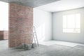 Sunny renovation room in light apartment with brick and white walls and ladder with buckets on concrete floor