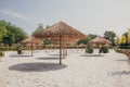 Sunny sandy beach with straw tiki umbrellas