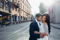 Sunny sensitive wedding portrait. Tenderly hugging beautiful couple of newlyweds in the town street.