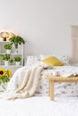 Sunny spring bedroom interior with green plants beside a bed dressed in eco cotton linen. Yellow accents Royalty Free Stock Photo