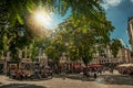 Sunny square with people talking on public stone seats in Brussels.