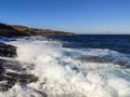 Sunny stormy blue sea waves on rocky shore, Greece