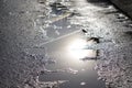 Sunny street after the rain. reflection, glare of the sun in puddles and wet asphalt, asphalt with holes in the city or village.