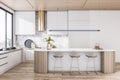 Sunny stylish dining area with white kitchen set, golden kitchen hood and countertop decorated by wooden laths on wooden floor and