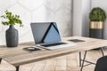 Sunny stylish home workspace with eco interior design: grey glossy clay pot with flowers, laptop, smartphone and digital tablet on Royalty Free Stock Photo
