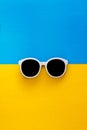 Sunny stylish white sunglasses on a bright blue-cyan and yellow-orange background, top view, isolated. Copy space. Flat lay