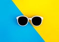 Sunny stylish white sunglasses on a bright blue-cyan and yellow-orange background, top view, isolated. Copy space. Flat lay