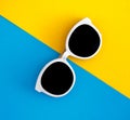 Sunny stylish white sunglasses on a bright blue-cyan and yellow-orange background, top view, isolated. Copy space. Flat lay Royalty Free Stock Photo