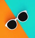 Sunny stylish white sunglasses on a bright blue-cyan and yellow-orange background, top view, isolated. Copy space. Flat Royalty Free Stock Photo