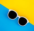 Sunny stylish white sunglasses on a bright blue-cyan and yellow-orange background, top view, isolated. Copy space. Flat Royalty Free Stock Photo