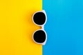 Sunny stylish white sunglasses on a bright blue-cyan and yellow-orange background, top view, isolated. Copy space. Flat lay Royalty Free Stock Photo