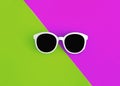 Sunny stylish white sunglasses on a bright green-cyan and crimson-pink background, top view, isolated. Copy space. Flat lay
