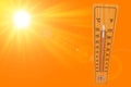 Sunny summer background with the thermometer marking a temperature over 40 degrees and bright sun on an orange background Royalty Free Stock Photo