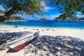 Sunny summer beach in Greece with sun beds and small boat. Agios Nikolaos Port Zakynthos island.