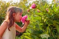 Happy little girl smelling fragrant pink peonies Royalty Free Stock Photo