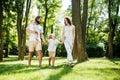Sunny summer day. Happy young family dressed in the white casual clothes walks in the park. Royalty Free Stock Photo