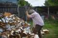 On a sunny summer day, a man is chopping firewood in the yard