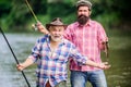 Sunny summer day at river. Fishing peaceful activity. Father and son fishing. Grandpa and mature man friends. Fisherman Royalty Free Stock Photo