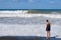 On a Sunny summer day, a teenager stands on the beach and watches the waves