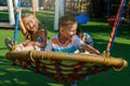 On sunny summer day, children swing on a swing in a playground in a public park Royalty Free Stock Photo