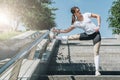 Sunny summer day. Young woman doing stretching exercises outdoor. Girl doing warm-up on steps before training. Royalty Free Stock Photo