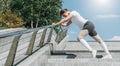 Sunny summer day. Young woman doing stretching exercises outdoor. Girl doing warm-up on steps before training. Workout. Royalty Free Stock Photo