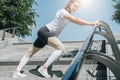 Sunny summer day. Young woman doing stretching exercises outdoor. Girl doing warm-up on steps before training. Workout. Royalty Free Stock Photo