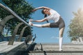 Sunny summer day. Young woman doing stretching exercises outdoor. Girl doing warm-up on steps before training. Royalty Free Stock Photo