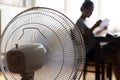 Sunny summer in front of the working fan, suffering from the summer heat. Unhappy Asian woman sitting in front of fan at work Royalty Free Stock Photo
