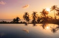 Sunny tropical landscape sunset with reflections of palm trees in surface of water in pool Royalty Free Stock Photo