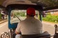 : the sunny view from inside the Tuk Tuk taxi, behind the driver as it is driven along a country road with the passenger`s reflec Royalty Free Stock Photo