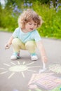 Cute toddler girl drawing with piece of color chalk.