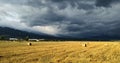 Sunny wheat field after harvest with dark dramatic clouds