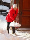 Sunny winter day. A woman after a heavy snowfall clears the area around a private house from snow with a shovel.The consequences