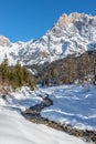 Sunny winter landscape in the alps: Mountain range, river, snowy trees, sunshine and blue sky Royalty Free Stock Photo