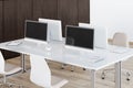 Sunny work space in modern style office with white furniture: tables and chairs and wooden wall and floor