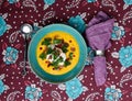 Healthy pumpkin soup, under the plate is a beautiful tablecloth with flowers.