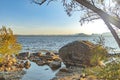 Sunray on background of large stones on seashore with mountains. Beautiful landscape of sea and mountains