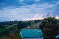 Sunrays break through heavy clouds behind golden vineyards in the valley, colourful trees on the slopes, and distant sea