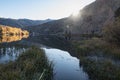 Sunrays bursting over mountain range and glowing on auatumn lake Royalty Free Stock Photo