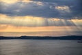 Sunrays shining through the clouds at sunset above the sea